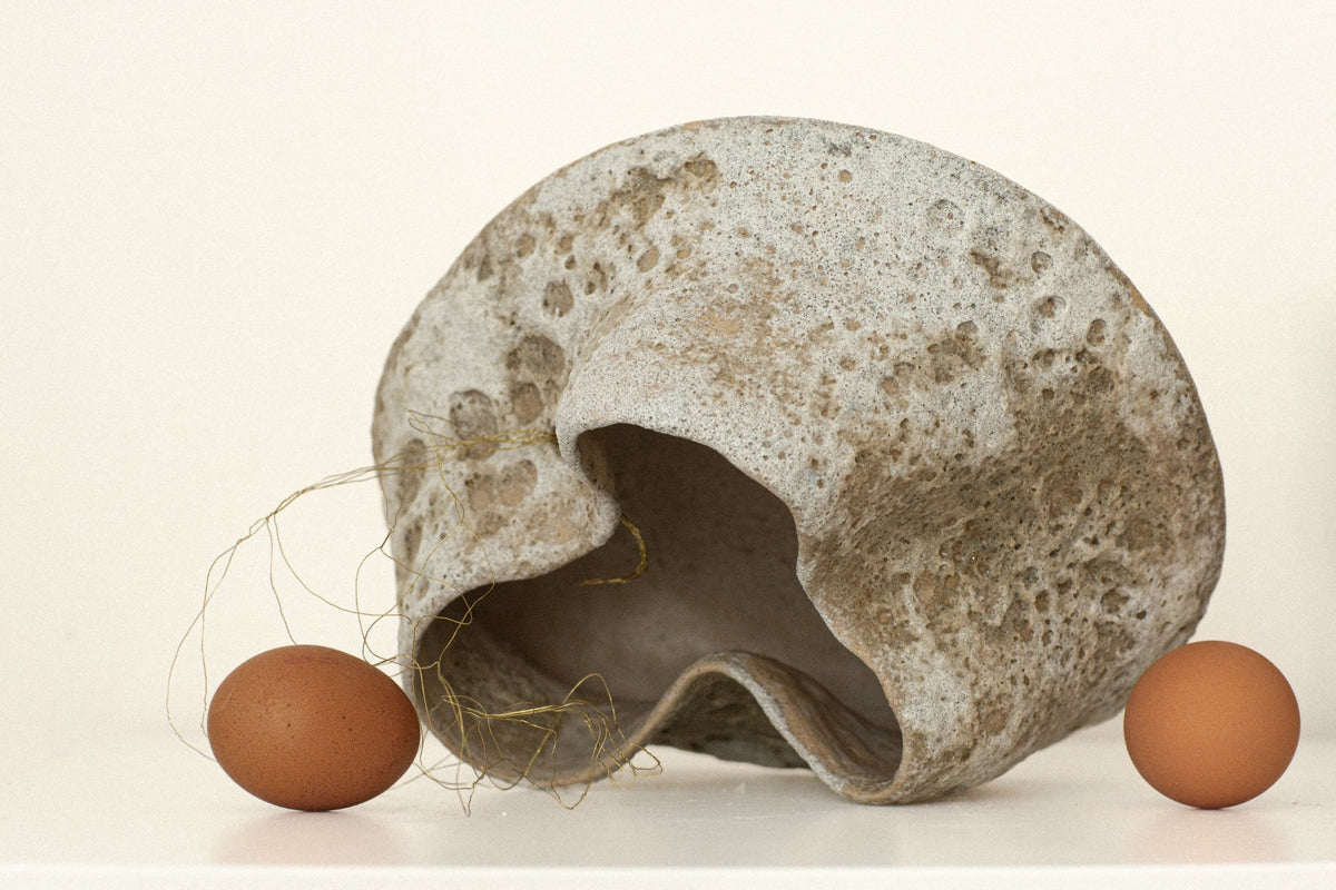 Sculptural ceramic vessel with gold-tone wire and eggs for scale